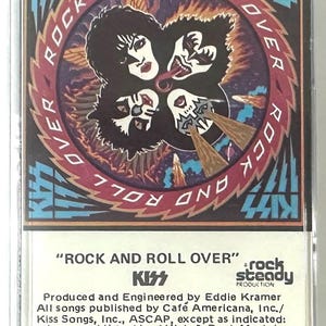 May include: A vintage cassette tape of the KISS album "Rock and Roll Over." The cover features the band's iconic makeup designs in a circular arrangement with the album title. The cassette is in a clear plastic case.