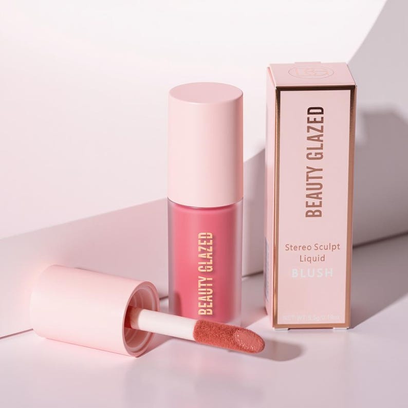 May include: A pink liquid blush product with a matching box. The blush is in a clear tube with a pink cap and a doe-foot applicator. The box and tube are labeled "BEAUTY GLAZED". The box also says "Stereo Sculpt Liquid BLUSH".