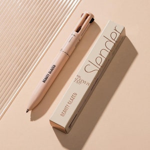 May include: A beige makeup pen with the text "BEAUTY GLAZED" and "MAKEUP PEN" printed on it. The pen has a retractable design with four different makeup tools. The pen is sitting on a beige surface next to a beige box with the text "Slender" printed on it.