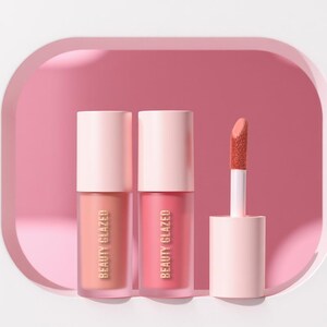 May include: Two tubes of lip gloss and one applicator with a pink and peach color scheme. The lip gloss tubes have a light pink cap and a clear body with the words "BEAUTY GLAZED" printed vertically. The applicator has a peach-colored tip.