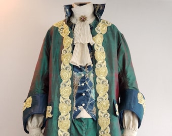 May include: A green and gold brocade jacket with a blue and gold patterned vest, white ruffled shirt, and green pants. The jacket has gold trim and a high collar.