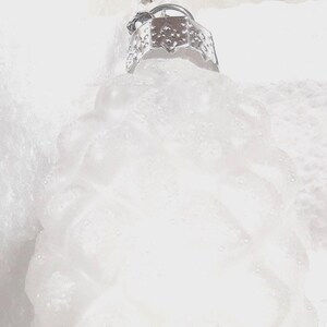 May include: A white, pinecone-shaped Christmas ornament with a textured, diamond-patterned surface covered in a light dusting of glitter. The ornament features a silver-colored metal cap at the top with a small loop for hanging purposes.