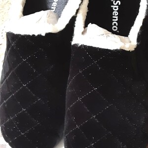 May include: Pair of black quilted velvet slippers with white faux fur lining. The slippers have a slip-on design and the brand name "Spenco" is visible on the insole.