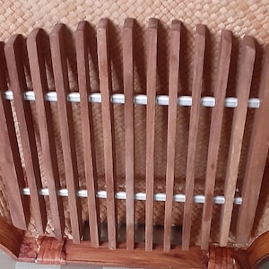 May include: Close-up of a chair back with a woven, light brown background. Vertical, dark brown wooden slats are evenly spaced and held together by two horizontal, silver-colored metal bars. The chair frame is also dark brown.