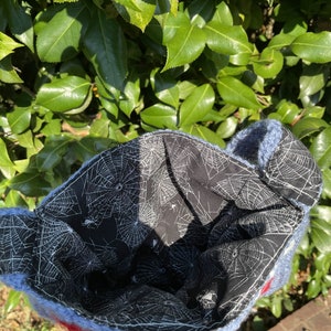 May include: Blue knitted bag with a spiderweb pattern lining. The bag is made of soft yarn and has a fluffy texture.