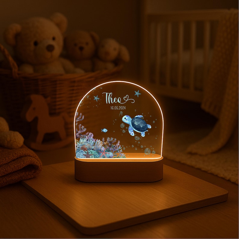 K&ouml;nnte beinhalten: Ein bogenf&ouml;rmiges Acryl-Nachtlicht mit Holzsockel, bedruckt mit einer Meeresschildkr&ouml;te, einem Korallenriff und Blasen. Der Text "Theo" und "16.05.2024" ist in wei&szlig;er Schreibschrift und serifenloser Schrift oben mittig aufgedruckt.