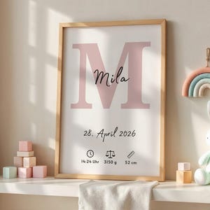 May include: A framed print with a light wood frame features a large pink letter "M" and the name "Mila" in cursive. Below, the date "28. April 2026" is printed, along with birth details: time, weight (3150 g), and length (52 cm).
