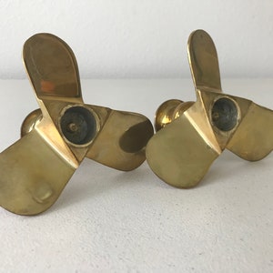 Puede incluir: Un par de candelabros de metal dorado con forma de h&eacute;lice de tres palas.