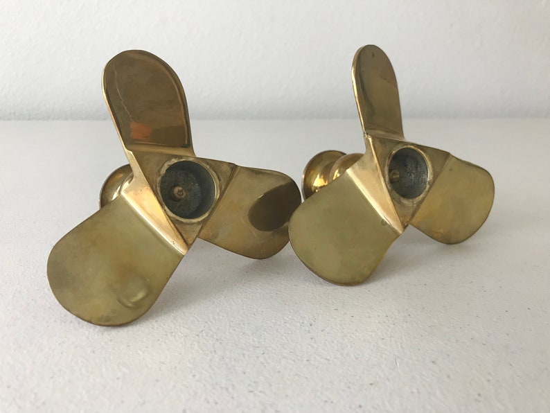 Puede incluir: Un par de candelabros de metal dorado con forma de h&eacute;lice de tres palas.