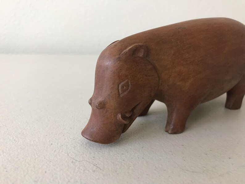K&ouml;nnte beinhalten: Eine handgeschnitzte Holzfigur eines Flusspferds. Das Flusspferd ist braun mit glatter Oberfl&auml;che und steht auf vier Beinen, der Kopf gesenkt. Die Figur hat geschnitzte Details, darunter eine rautenf&ouml;rmige Markierung auf der Stirn.