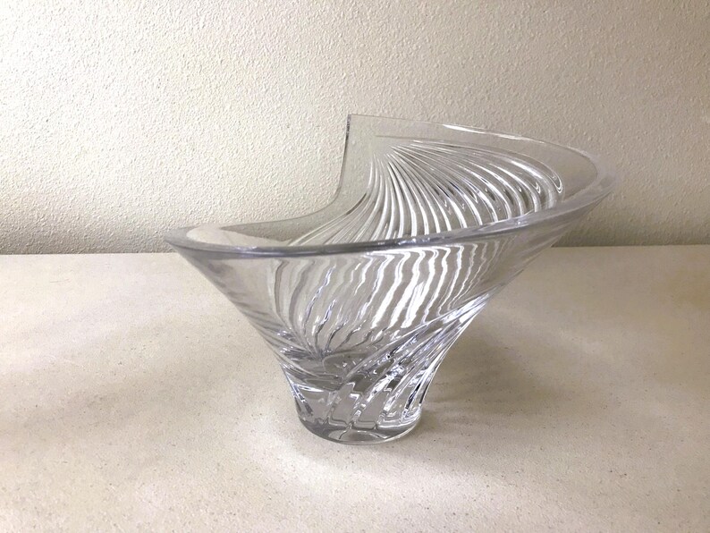 Pode incluir: Tigela decorativa de vidro transparente com uma forma assim&eacute;trica incomum. A tigela apresenta um padr&atilde;o de redemoinho e texturizado no exterior, criando um efeito visual din&acirc;mico. O design &eacute; elegante e moderno, adequado para exibi&ccedil;&atilde;o ou servir.