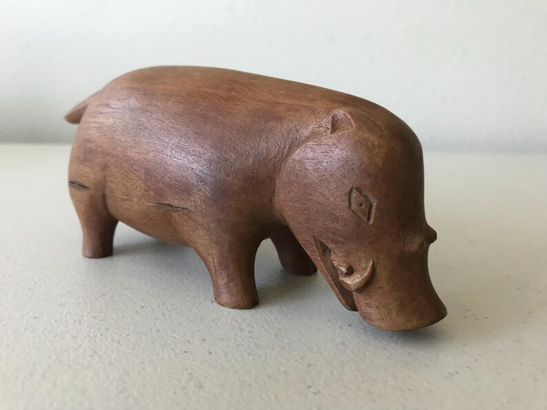 K&ouml;nnte beinhalten: Eine handgeschnitzte Holzfigur eines Nilpferds. Das braune Nilpferd hat ein detailliertes Design mit sichtbaren geschnitzten Merkmalen. Die Figur steht auf vier Beinen, mit gesenktem Kopf. Die Holzmaserung ist sichtbar.