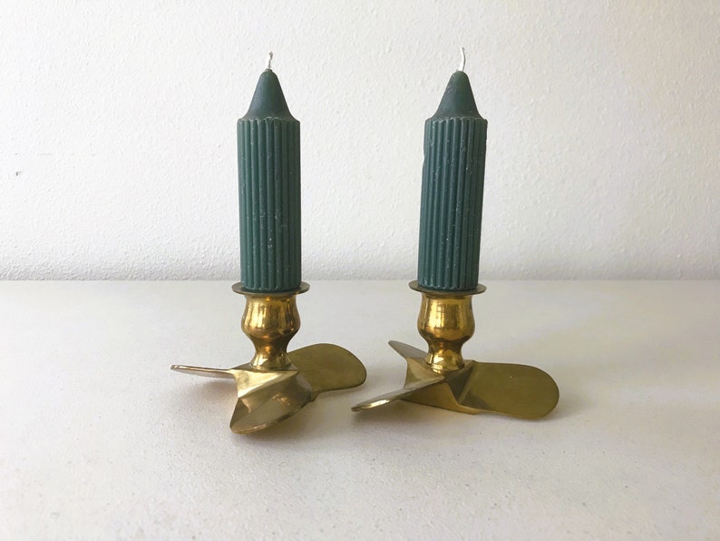 Puede incluir: Dos candelabros de lat&oacute;n con bases en forma de h&eacute;lice y velas de color verde oscuro.