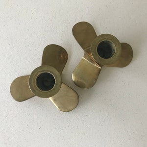 Puede incluir: Dos candelabros de metal dorado, cada uno con tres brazos. Los candelabros tienen forma de h&eacute;lice.