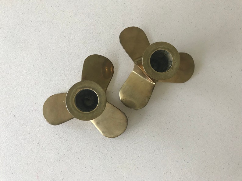Puede incluir: Dos candelabros de metal dorado, cada uno con tres brazos. Los candelabros tienen forma de h&eacute;lice.