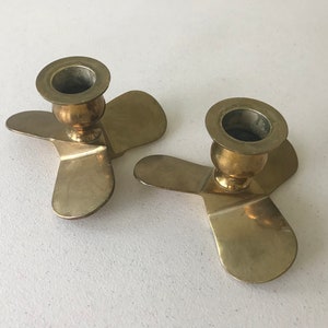 Puede incluir: Dos candelabros de metal dorado con una base de tres puntas en forma de h&eacute;lice.