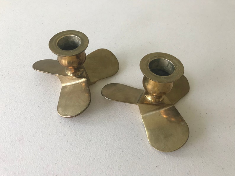 Puede incluir: Dos candelabros de metal dorado con una base de tres puntas en forma de h&eacute;lice.