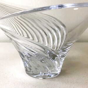 Pode incluir: Tigela decorativa de vidro transparente com um design &uacute;nico em espiral. A tigela tem uma parte superior larga e aberta e um padr&atilde;o texturizado e canelado que se enrola para baixo at&eacute; uma base s&oacute;lida. O vidro &eacute; transparente.