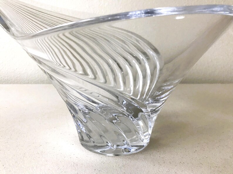Pode incluir: Tigela decorativa de vidro transparente com um design &uacute;nico em espiral. A tigela tem uma parte superior larga e aberta e um padr&atilde;o texturizado e canelado que se enrola para baixo at&eacute; uma base s&oacute;lida. O vidro &eacute; transparente.