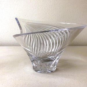 Pode incluir: Tigela de vidro transparente com uma forma assim&eacute;trica incomum. O exterior da tigela apresenta um padr&atilde;o texturizado e rodopiante, criando um efeito canelado. O design &eacute; moderno e elegante, adequado para fins decorativos ou de servi&ccedil;o.