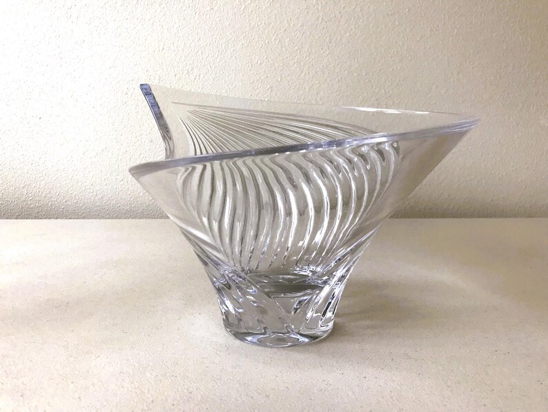 Pode incluir: Tigela de vidro transparente com uma forma assim&eacute;trica incomum. O exterior da tigela apresenta um padr&atilde;o texturizado e rodopiante, criando um efeito canelado. O design &eacute; moderno e elegante, adequado para fins decorativos ou de servi&ccedil;o.