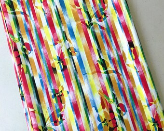 May include: A vibrant fabric with a striped pattern in red, yellow, blue, and orange. The design features vertical brushstrokes and floral accents. The fabric's bright colors and floral elements create a cheerful and artistic aesthetic.