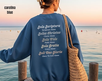 May include: A Carolina blue crew neck sweatshirt with the words "Sola Scriptura" and other religious phrases printed on the back in white script. The words "carolina blue" are in the upper left corner.