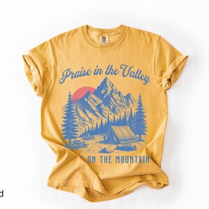 Elevation Brandon Lake Fan Shirt Praise in the Valley Praise on the Mountain Comfort Colors 1717 tee,tshirt in neutral colors trendy with praise in the valley in cursive font and praise on the mountain in a sans serif witha blue print of a mountain