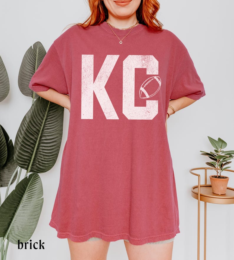 A simple textured looking KC printed on a soft and durable comfort colors 1717 tshirt- with an outline of a football in the letter C- perfect for game day or any Red Friday in Kansas City to celebrate the Chiefs