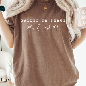 May include: A brown t-shirt with the text "Called to Serve Mark 10:45" printed in white.