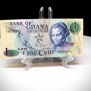 May include: A one Cedi banknote from Ghana, dated 2nd Jan 1976. The note features a portrait of a woman with a headset, a star with the words "Bank of Ghana" and the text "One Cedi" in blue.