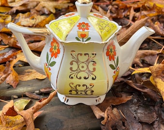white and orange flowers tea pot