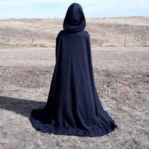 K&ouml;nnte beinhalten: Ein schwarzer Kapuzenumhang mit einem langen, flie&szlig;enden Design. Der Umhang ist aus einem weichen, bequemen Stoff gefertigt und perfekt, um jedem Outfit einen Hauch von Geheimnis und Intrige zu verleihen.