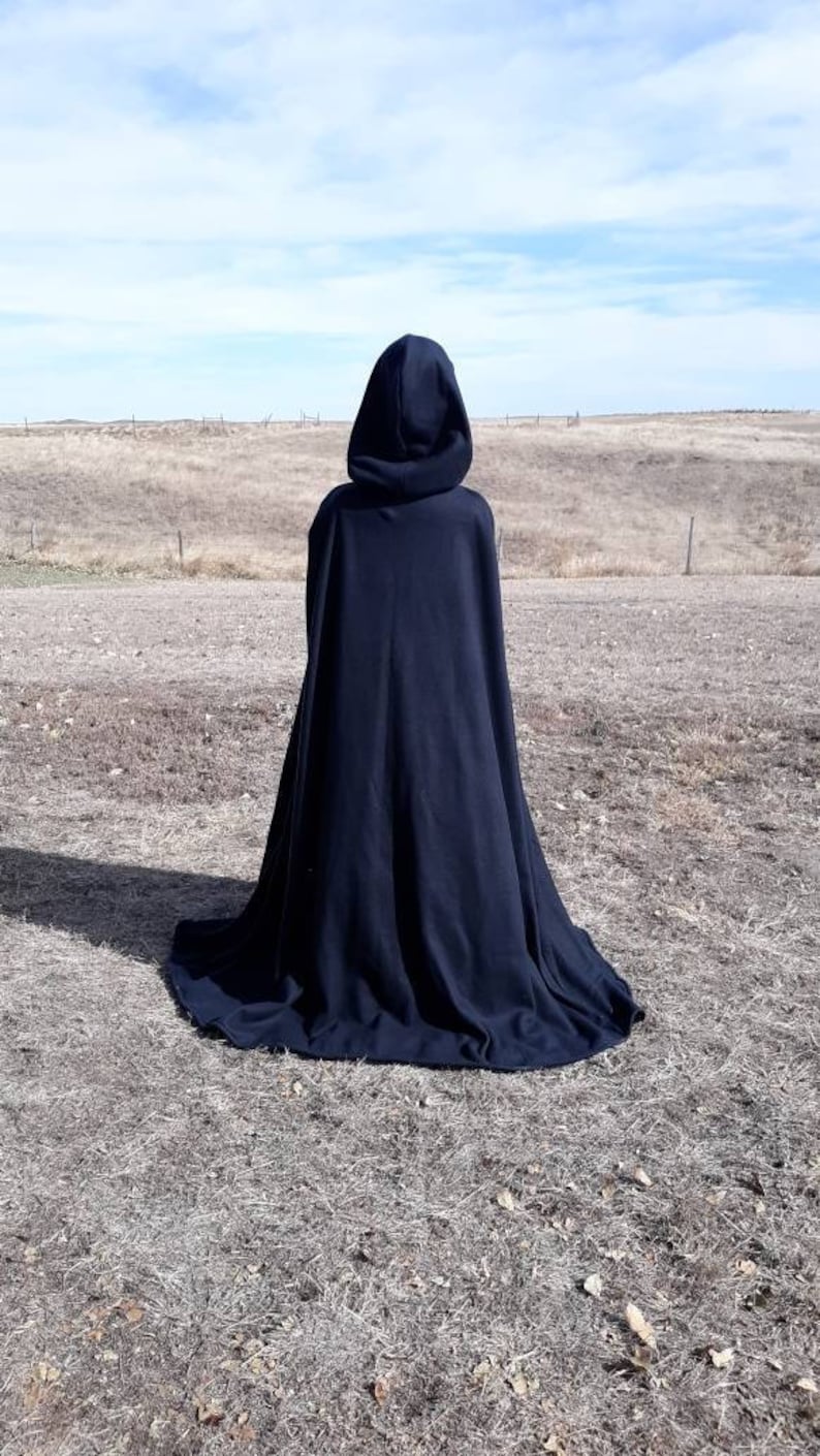 K&ouml;nnte beinhalten: Ein schwarzer Kapuzenumhang mit einem langen, flie&szlig;enden Design. Der Umhang ist aus einem weichen, bequemen Stoff gefertigt und perfekt, um jedem Outfit einen Hauch von Geheimnis und Intrige zu verleihen.