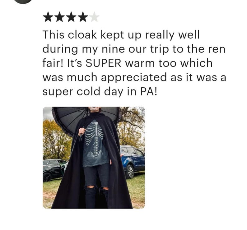 K&ouml;nnte beinhalten: Eine Person tr&auml;gt einen schwarzen Umhang mit einem Skelett-Shirt und zerrissenen Jeans. Die Person h&auml;lt einen schwarzen Regenschirm und steht vor einem Auto.