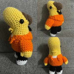 Op de afbeelding: Drie gehaakte knuffels in de vorm van een vogel. De knuffels zijn geel en oranje met zwarte ogen. De knuffels dragen oranje jassen en zwarte broeken.