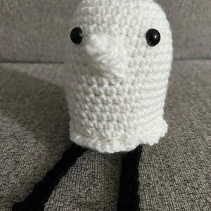 May include: White crocheted ghost with black yarn legs and black button eyes.