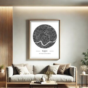 Może przedstawiać: Oprawiona czarno-biała mapa Krakowa, Polska, wisi w nowoczesnym salonie. Okrągła mapa przedstawia układ miasta. Pokój ma neutralną kolorystykę, drewniany stolik kawowy i lampę podłogową. Rama jest złota.