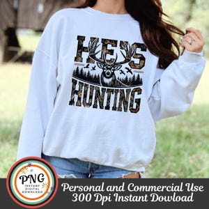 May include: White sweatshirt with a camouflage pattern and the text "Hey's Hunting" with a deer silhouette in the center.