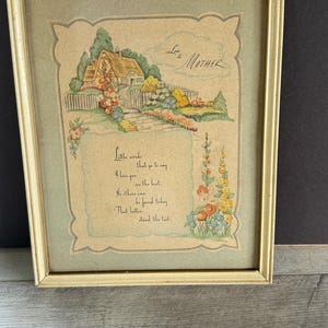 May include: Framed vintage print with a cottage scene, flowers, and the words "Love to Mother." The artwork features a quaint house, a garden path, and a handwritten poem. The frame is a light cream color.