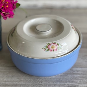 May include: A vintage blue and white ceramic casserole dish with a floral design. The dish has a lid and is perfect for serving a meal.