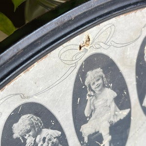May include: A vintage oval picture frame with a black wooden frame and a white mat. The frame contains three black and white photos of young girls. The photos are oval shaped and have a decorative border. The text "The Three Sisters" is printed on the bottom of the frame.
