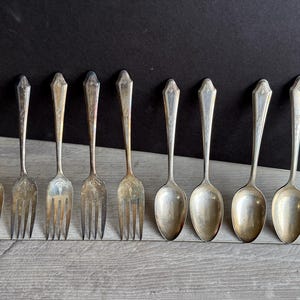 May include: A set of ten silver-plated utensils, including five forks and five spoons. The utensils have ornate designs and are in good condition.