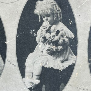 May include: Black and white photo of a young girl in a white dress holding a bouquet of flowers. The photo is in an oval frame with the word "SMELLING" printed below it.