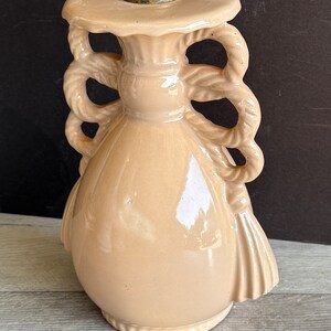 May include: A pale pink ceramic table lamp with a rope-like design on the base and a brass socket.
