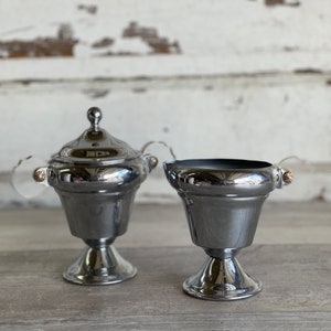 May include: A silver creamer and sugar bowl set with ornate handles and a classic design.