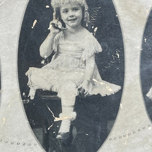 May include: Black and white photo of a young girl in a white dress holding a toy telephone. The photo is framed in an oval and is part of a larger image depicting the five senses. The text "Hearing" and "The Five Senses" is visible below the photo.