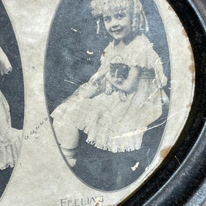May include: A vintage metal tray with a black rim and a white interior. The tray features three oval-shaped images of young girls. The text "Feeling" is printed on the bottom of the tray.