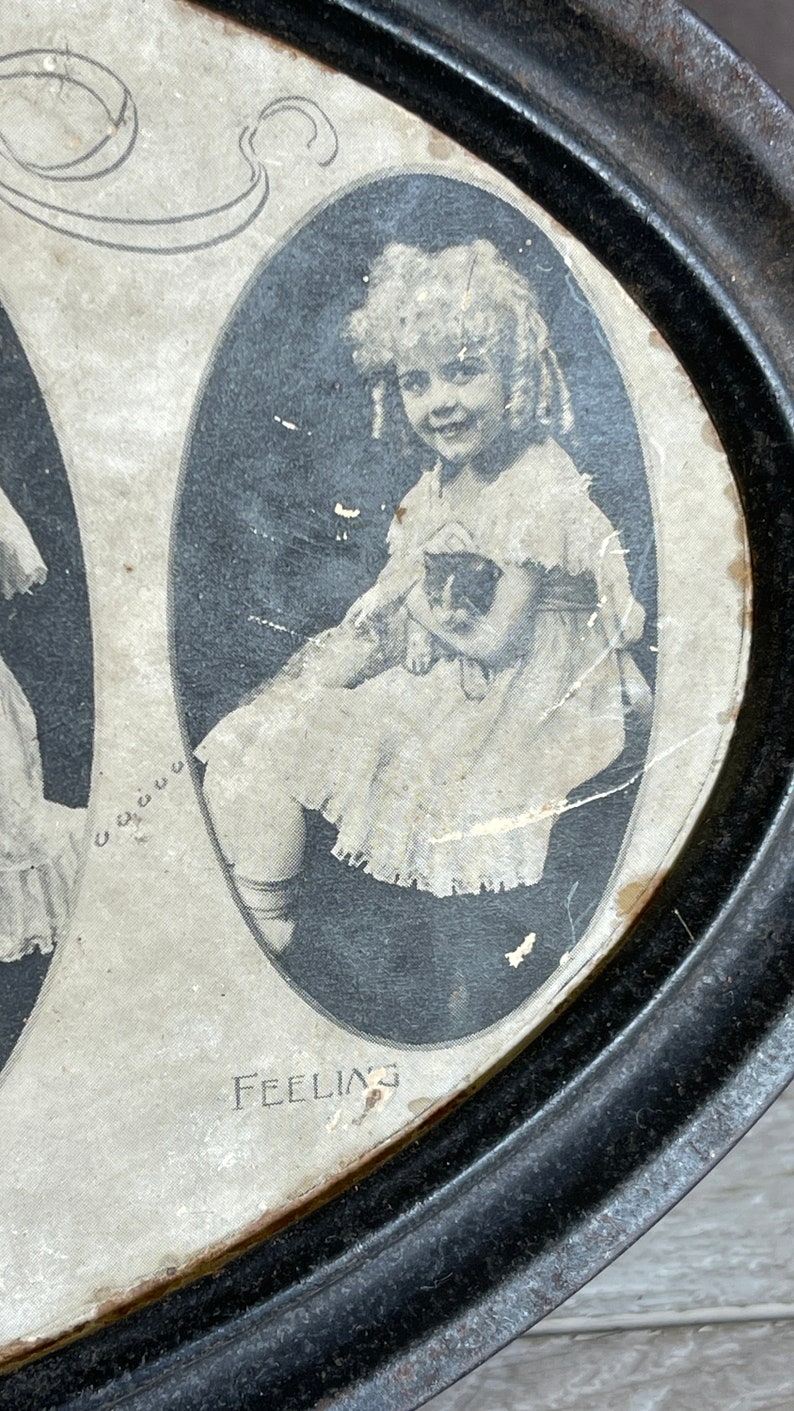 May include: A vintage metal tray with a black rim and a white interior. The tray features three oval-shaped images of young girls. The text "Feeling" is printed on the bottom of the tray.