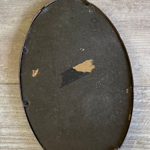 May include: A black oval picture frame with a dark brown mat. The frame has a slight curve to it and is made of wood.
